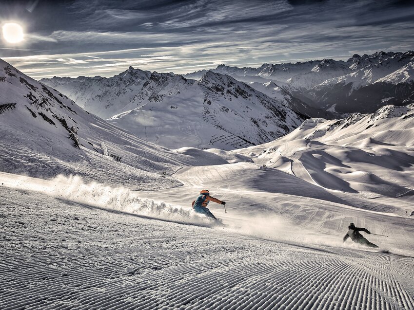 Perfekt präparierte Skipiste mit zwei sportlichen SkifahrerInnen im Skigebiet Silvretta Montafon – dem größten und sportlichsten Skigebiet im Montafon Brandnertal in den österreichischen Alpen. | © Silvretta Montafon Bergbahnen GmbH, Daniel Zangerl